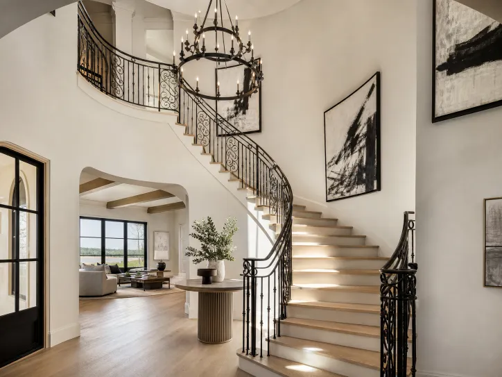 Grand curved staircase in a light-filled two-story foyer. Conceptual imagery — not an active listing.